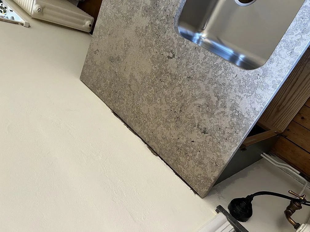 Köksbänkskiva i Jura Grey, grå kalksten med matt yta, med underlimmad rostfri diskho i en köksö under montering i ett kök i Malmö.
