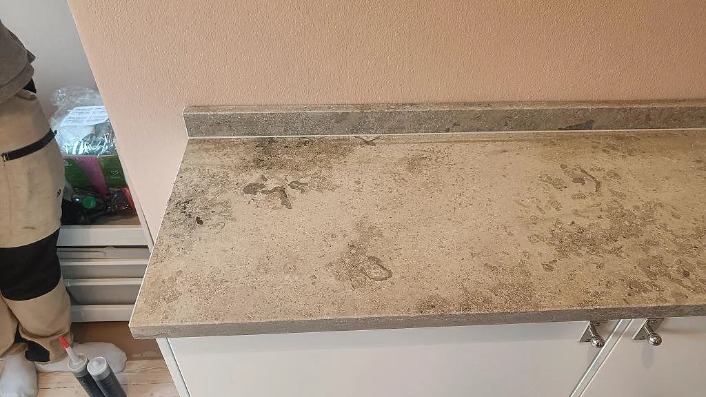 Detalj av Jura Grey kalksten med matt yta och låg stänkkant på en kökshalvö i Malmö.