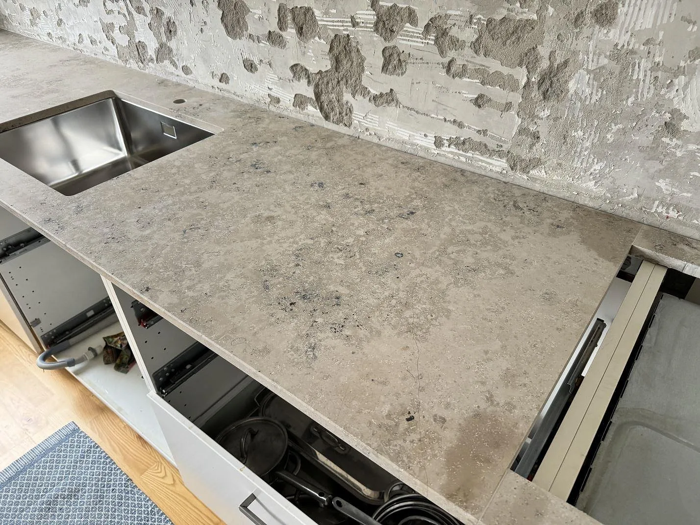 Närbild på köksbänkskiva i matt Jura Grey med grå stenstruktur och rostfri diskho vid renovering i Malmö.