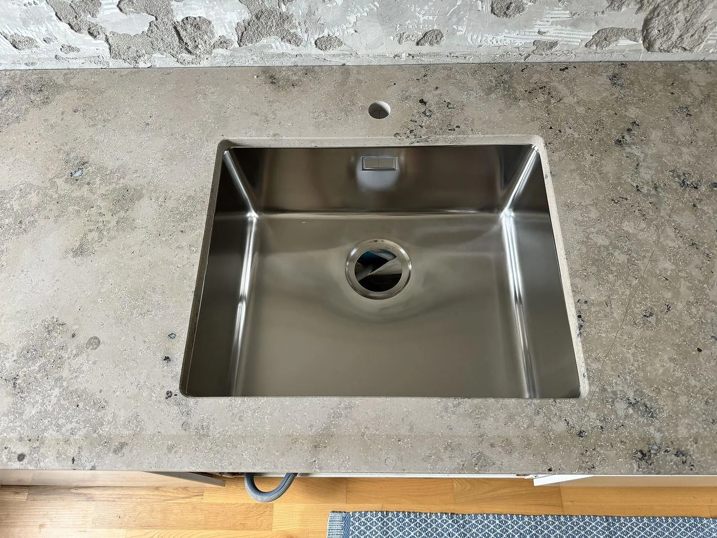 Rostfri diskho i köksbänkskiva av matt Jura Grey, med blandarhål och grå kalkstensyta i Malmö.