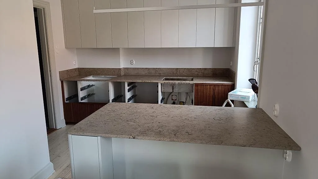Köksbänkskivor i Jura Grey, matt kalksten, med köksö och uppvikt stänkkant i ett kök i Malmö.