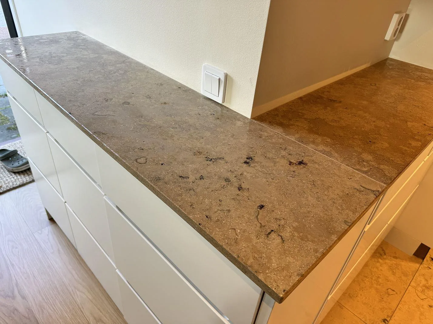 Matt Jura Grey kalksten som köksbänkskiva längs en väggnisch med vit förvaring i Malmö.