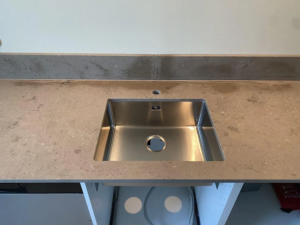 Matt Jura Grey bänkskiva med rostfri diskho och låg stänkkant i ett kök i Malmö.