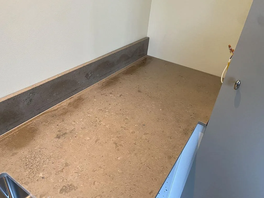 Hörndel av köksbänkskiva i matt Jura Grey kalksten med stänkkant under montering i Malmö.