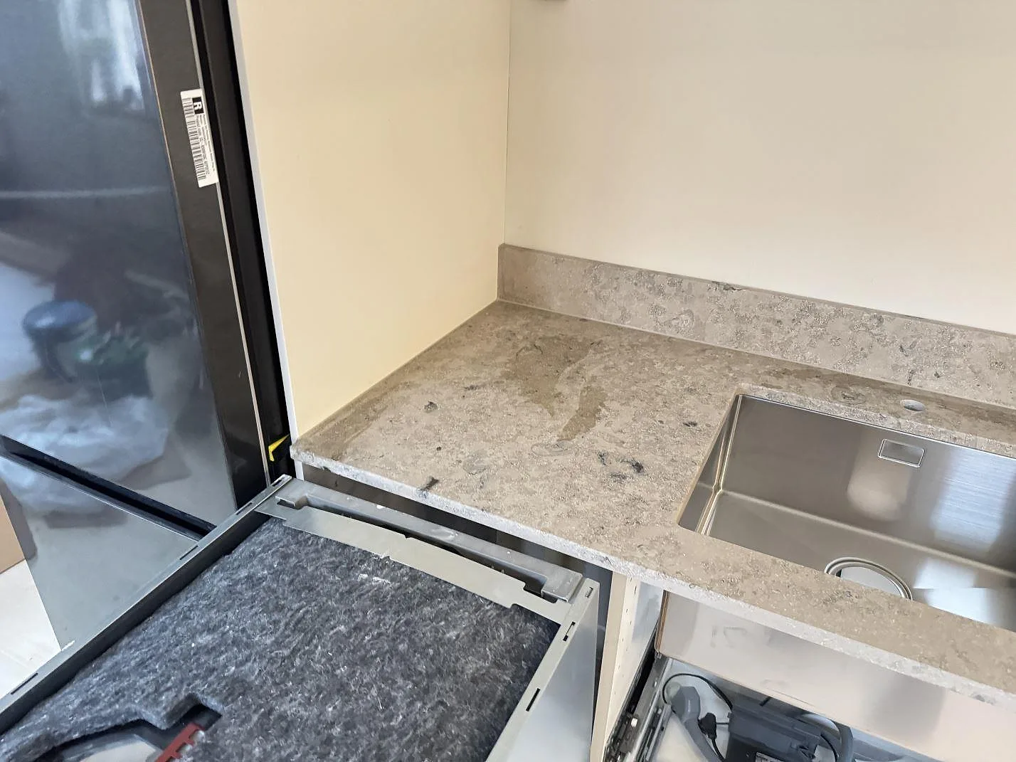 Matt köksbänkskiva i Jura Grey med stänkkant och diskho under montering i Malmö.