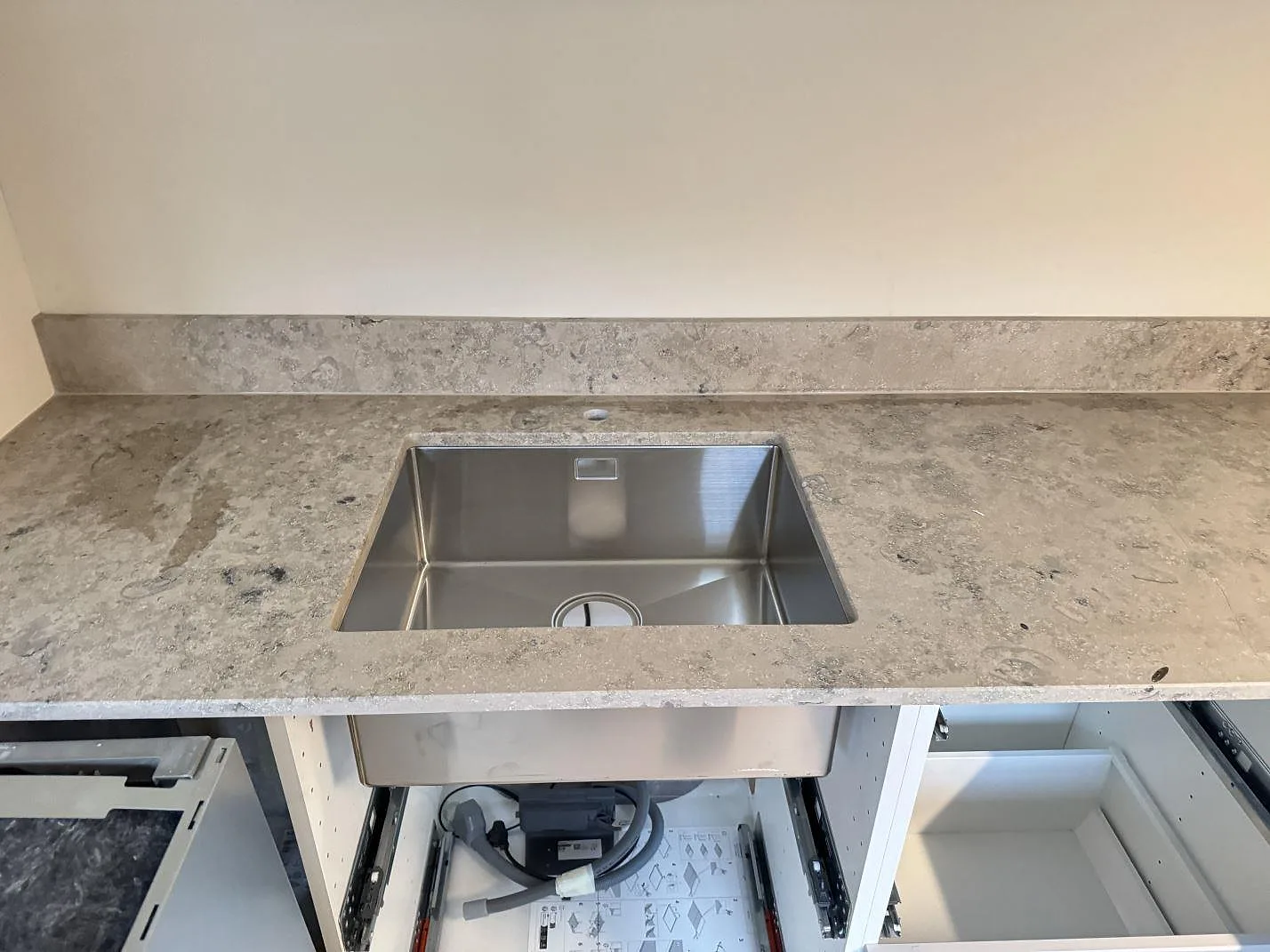 Köksbänkskiva i matt Jura Grey, 20 mm, med rostfri diskho och låg stänkkant i ett kök i Malmö.