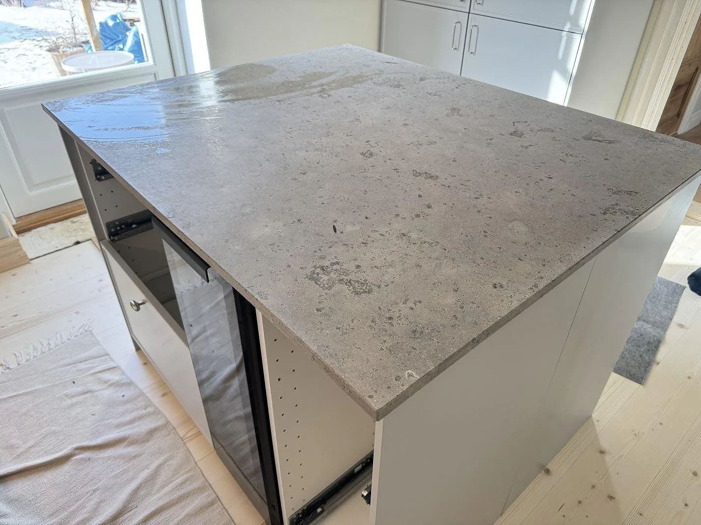 Köksbänkskiva i Jura Grey kalksten, matt yta, monterad som friliggande köksö med synlig kant i ett kök under inredning i Malmö.