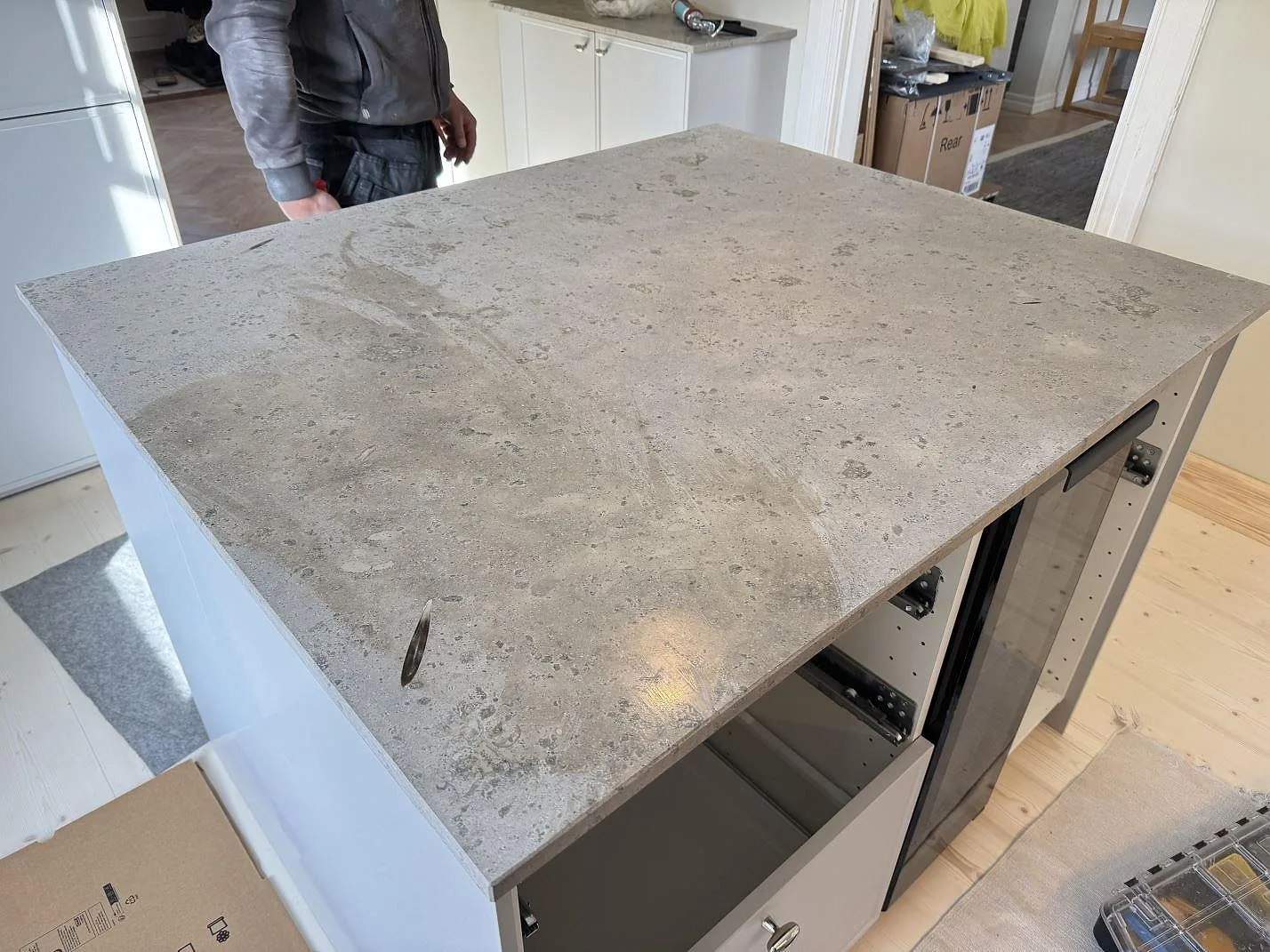 Köksö i matt Jura Grey kalksten med fossilprickig grå struktur över vita köksstommar i ett kök i Malmö.