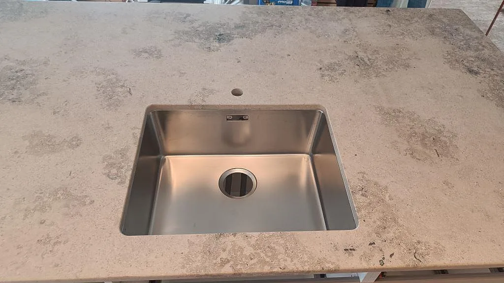 Rostfri diskho i en matt Jura Grey bänkskiva med gråbeige kalkstensyta i Marstrand.