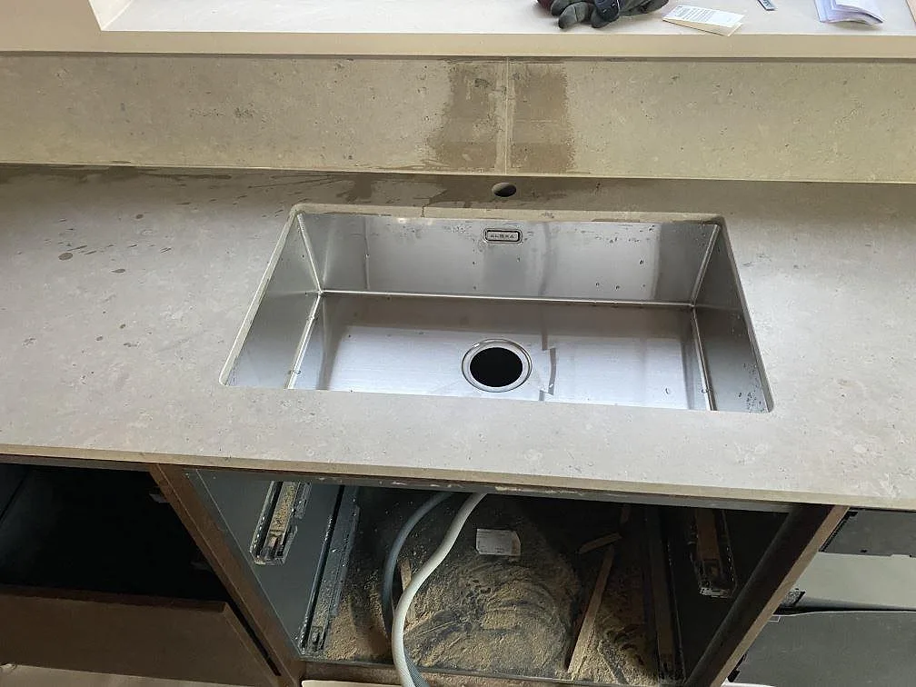 Underlimmad rostfri diskho i matt Jura Grey kalksten med uppvikt stänkkant under fönster i Mölndal.