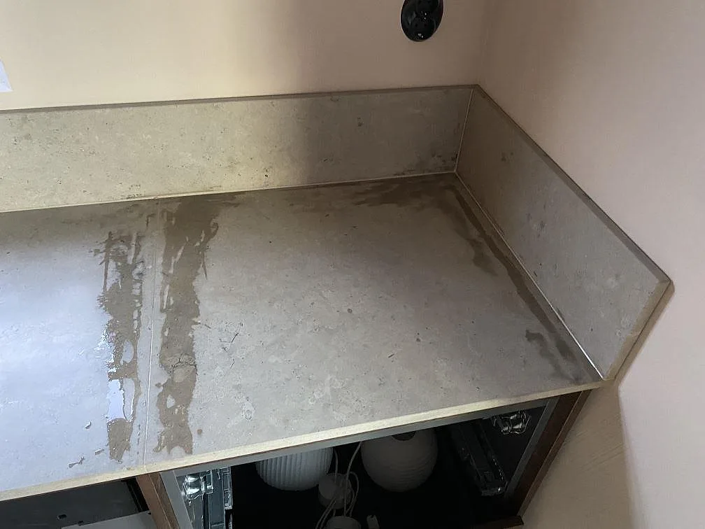 Hörnparti med matt Jura Grey kalkstensbänk och stänkkant i samma sten i ett kök i Mölndal.