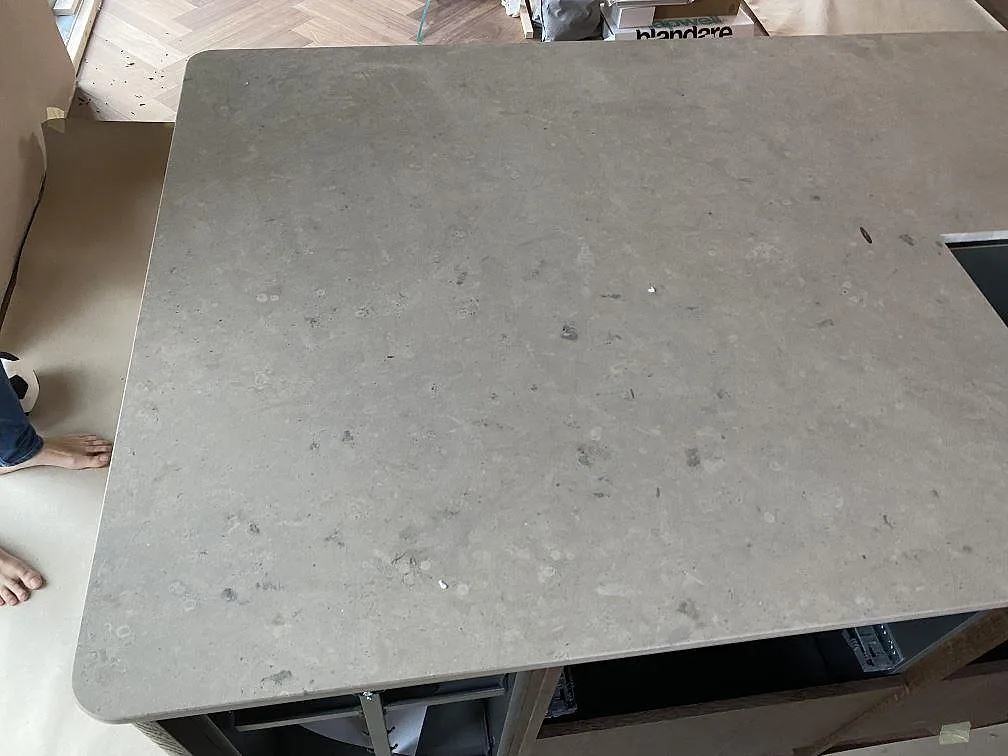 Köksö med stor matt Jura Grey kalkstensskiva, rundad kant och synligt urtag under montering i Mölndal.