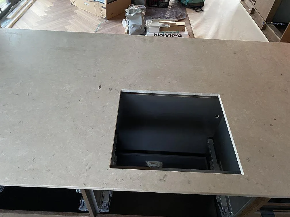 Köksö i matt Jura Grey kalksten med rektangulärt svart urtag och tydlig fossilstruktur under montering i Mölndal.