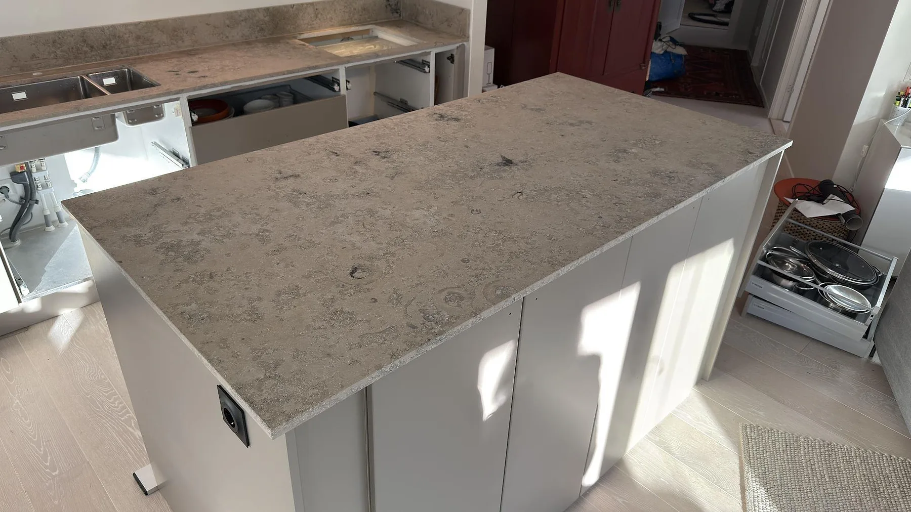 Närbild av köksö i matt Jura Grey med fossil ådring och gråbeige naturstensyta i ett kök i Nacka.