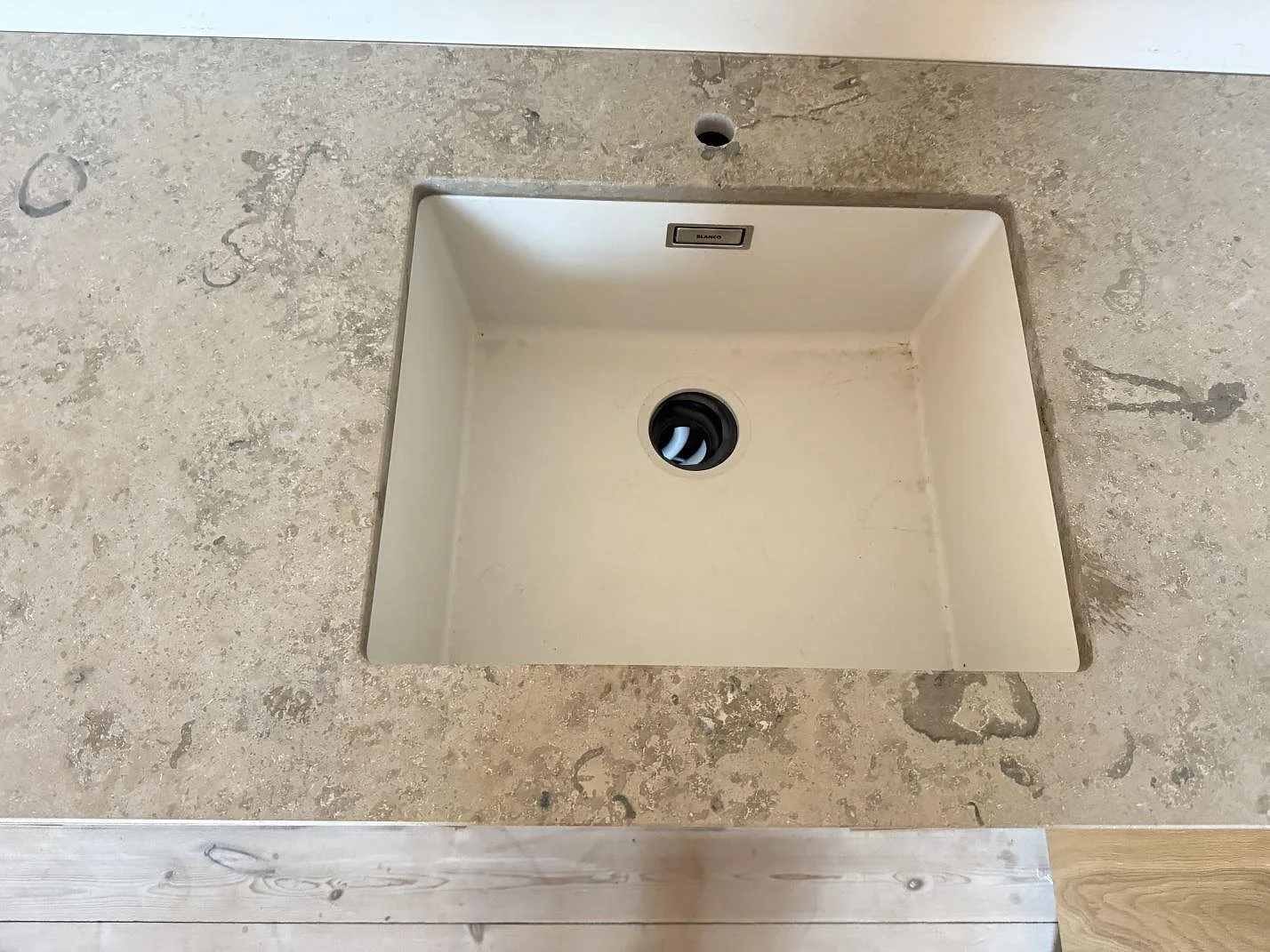Underlimmad ljus diskho sedd ovanifrån i matt Jura Grey kalksten i ett kök i Nivå.