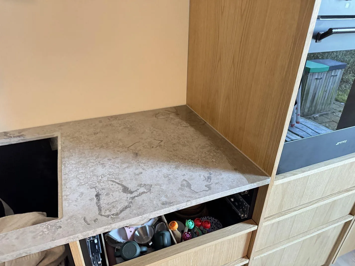 Köksbänkskiva i Jura Grey kalksten med håltagning för häll och utdragen låda, fotad under montering i ett kök i Nivå.