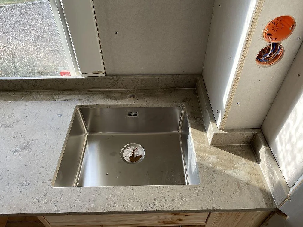 Närbild av matt Jura Grey bänkskiva vid diskzonen med grå ådring och stänkkant i Ronneby.