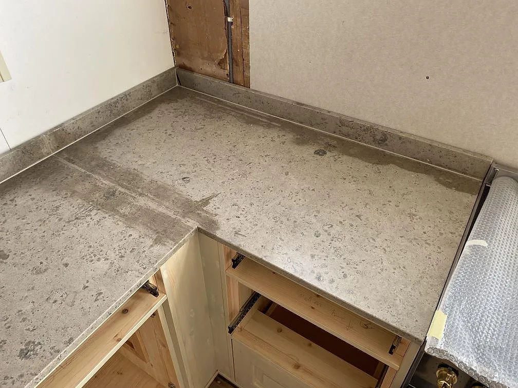 Hörnparti med matt Jura Grey bänkskiva och uppvikt stänkkant på öppna köksstommar i Ronneby.