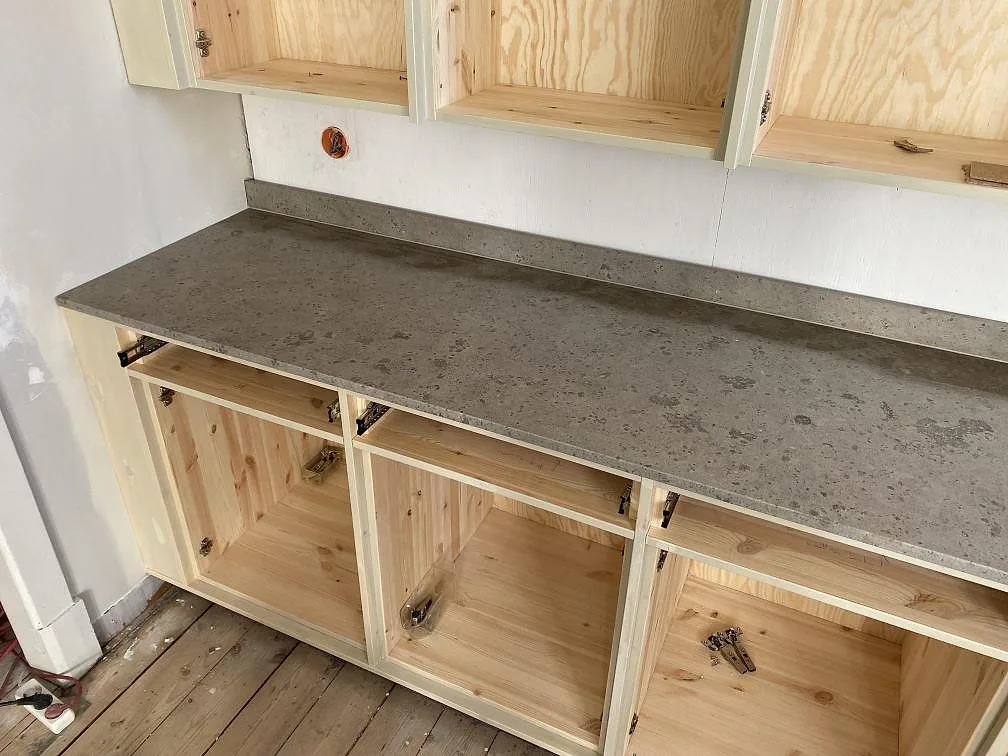 Matt Jura Grey köksbänkskiva med uppvikt stänkkant över öppna trästommar under montering i Ronneby.
