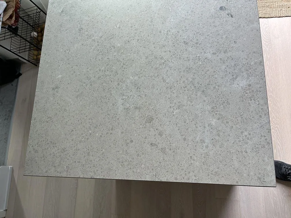 Närbild ovanifrån av matt Jura Grey köksbänkskiva med fossil struktur och grå kalkstensyta i Saltsjö Boo.