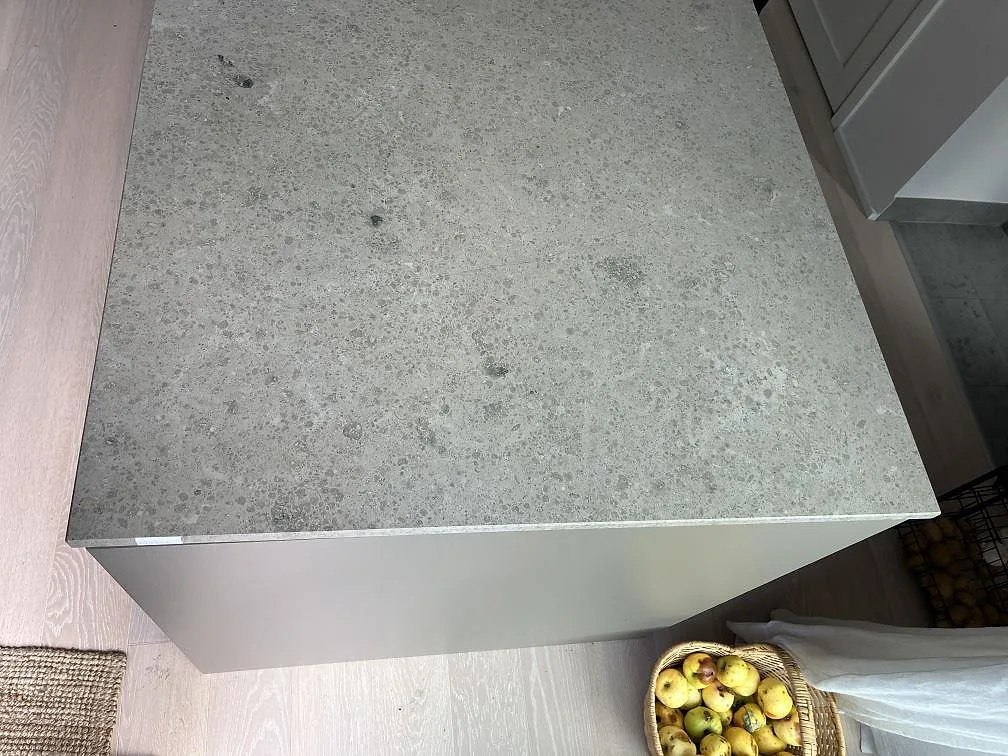 Köksbänkskiva i matt Jura Grey kalksten, 20 mm, på en vit köksö eller halvö i Saltsjö Boo.