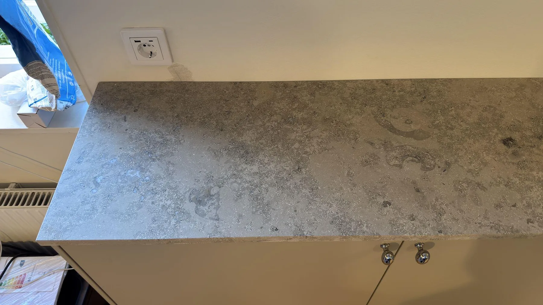 Närbild av matt Jura Grey bänkskiva med grå fossilstruktur på en skåpsdel i Saltsjö Boo.