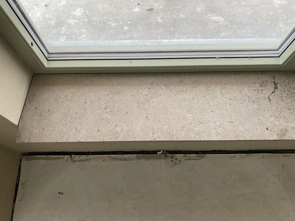 Närbild på matt Jura Grey fönsterbänk i kalksten, 20 mm, under ett stort fönster i Sankt Olof.