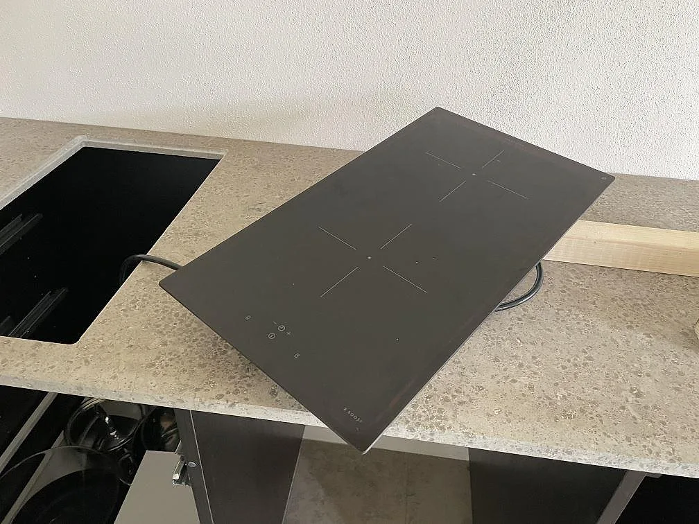 Köksbänkskiva i matt Jura Grey kalksten med svart häll löst placerad över hällurtaget under montering i Skanör.