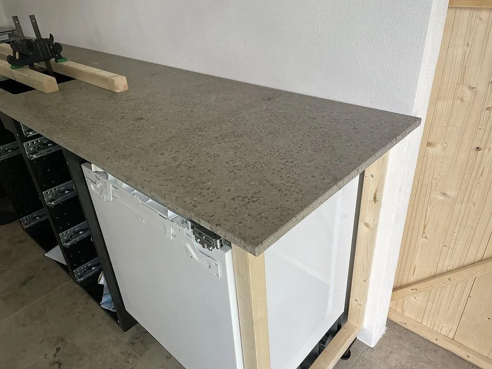 Köksbänkskiva i matt Jura Grey kalksten, 20 mm, monterad på köksstommar under montering i Skanör.