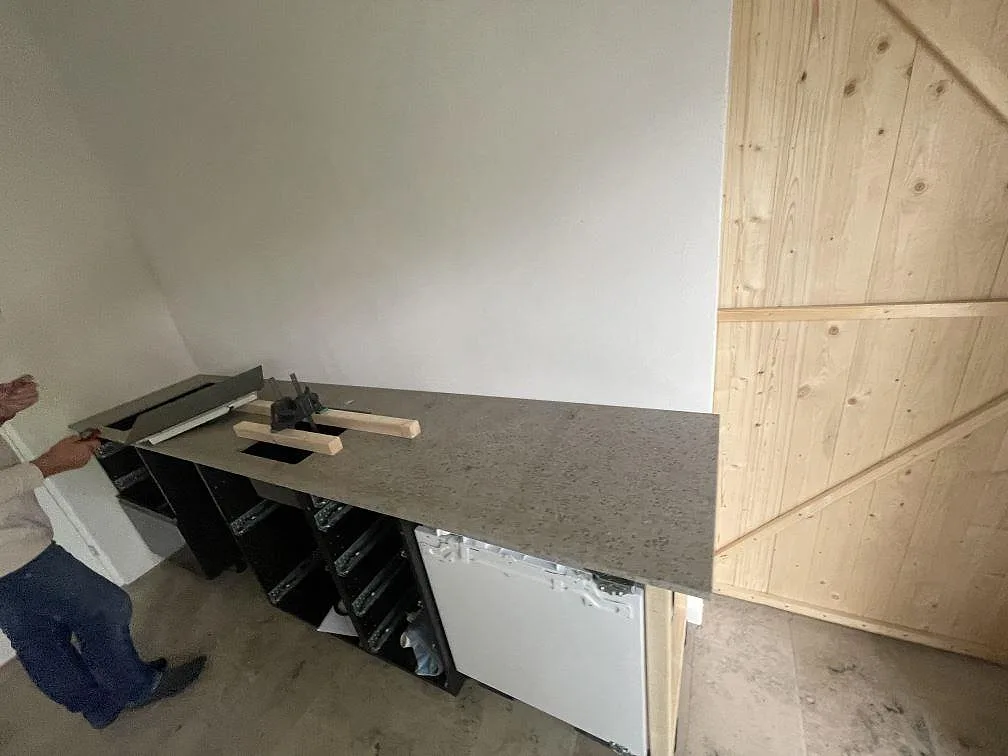 Matt köksbänkskiva i Jura Grey kalksten med hällurtag och monteringsklämmor i ett kök under montering i Skanör.