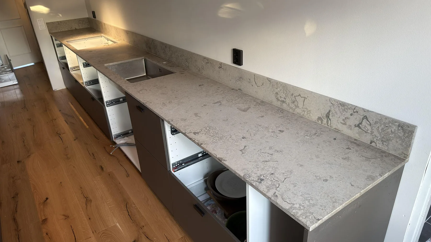 Matt Jura Grey kalksten som köksbänkskiva med diskho och uppvikt stänkkant längs väggen i Stenhamra.