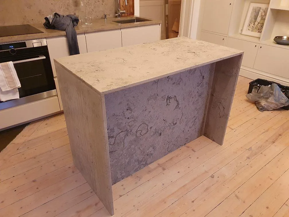 Köksö och bänkskiva i matt Jura Grey, grå kalksten med fossil ådring, under montering i ett kök i Stockholm.