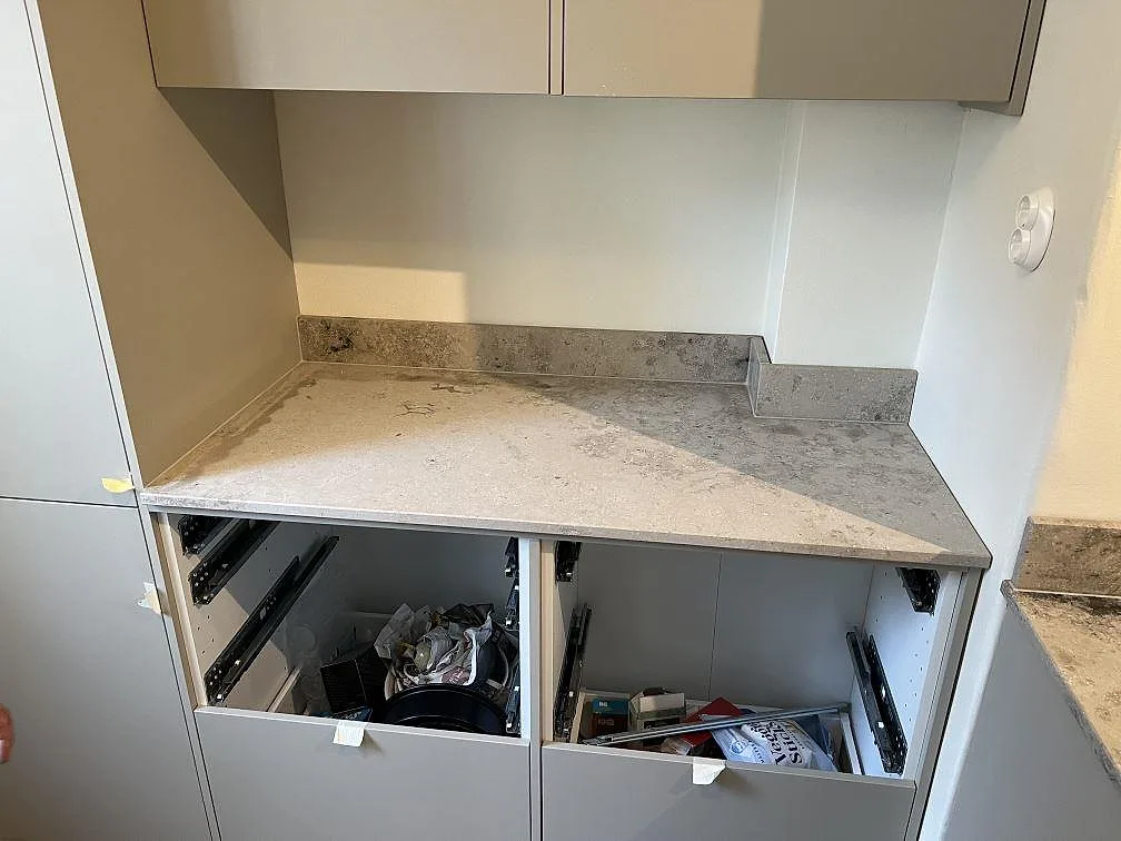 Rak köksbänkskiva i matt Jura Grey med låg stänkkant under väggskåp i Stockholm.
