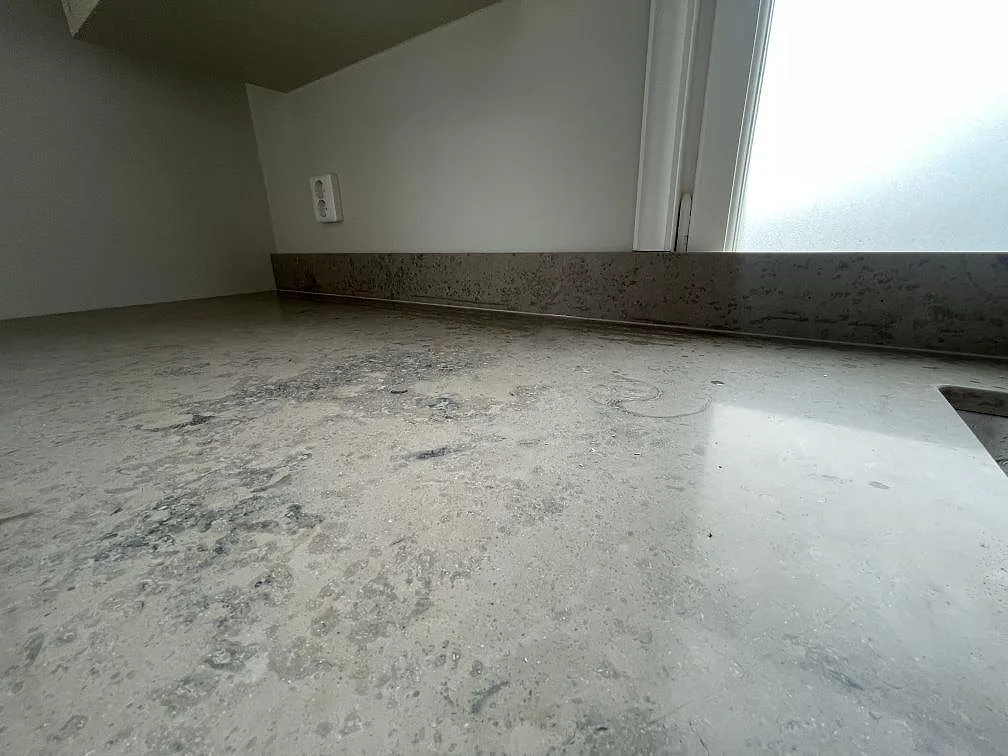 Detaljbild av den matta Jura Grey kalkstenen med levande mönster och låg stänkkant i köket i Stockholm.