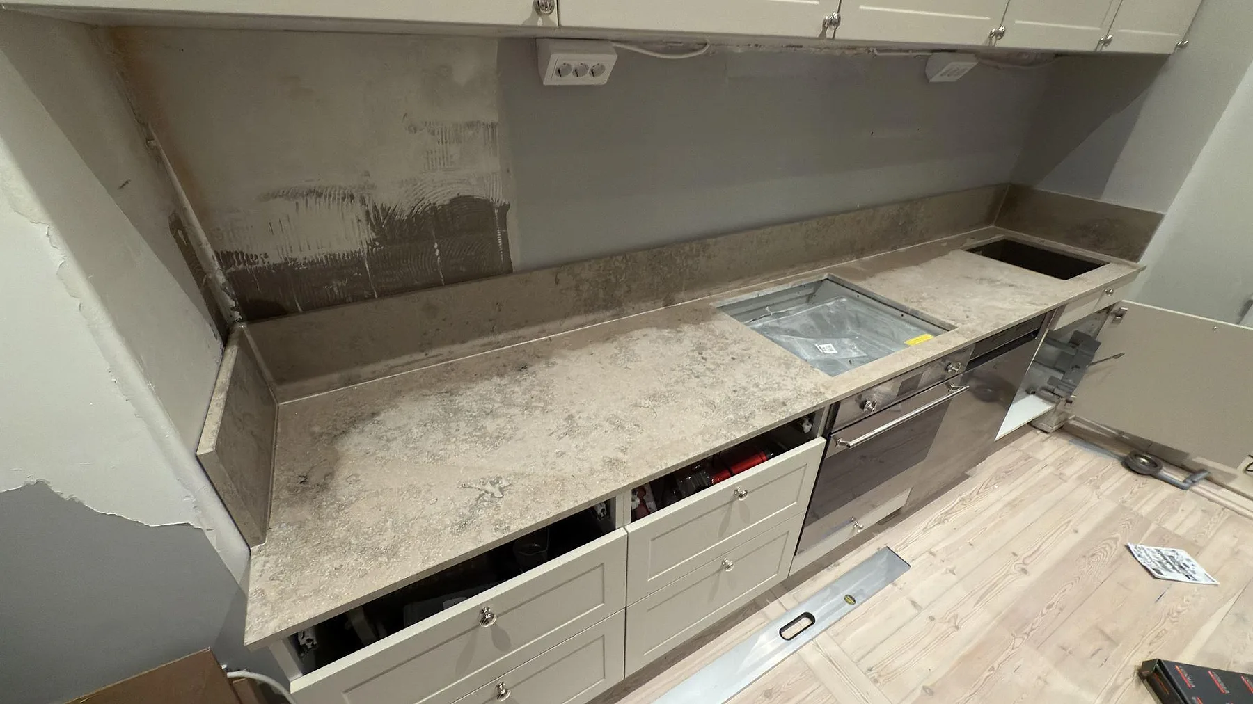 Köksbänkskiva i matt Jura Grey kalksten med hällplats, stänkkant och arbetsyta under montering i Stockholm.