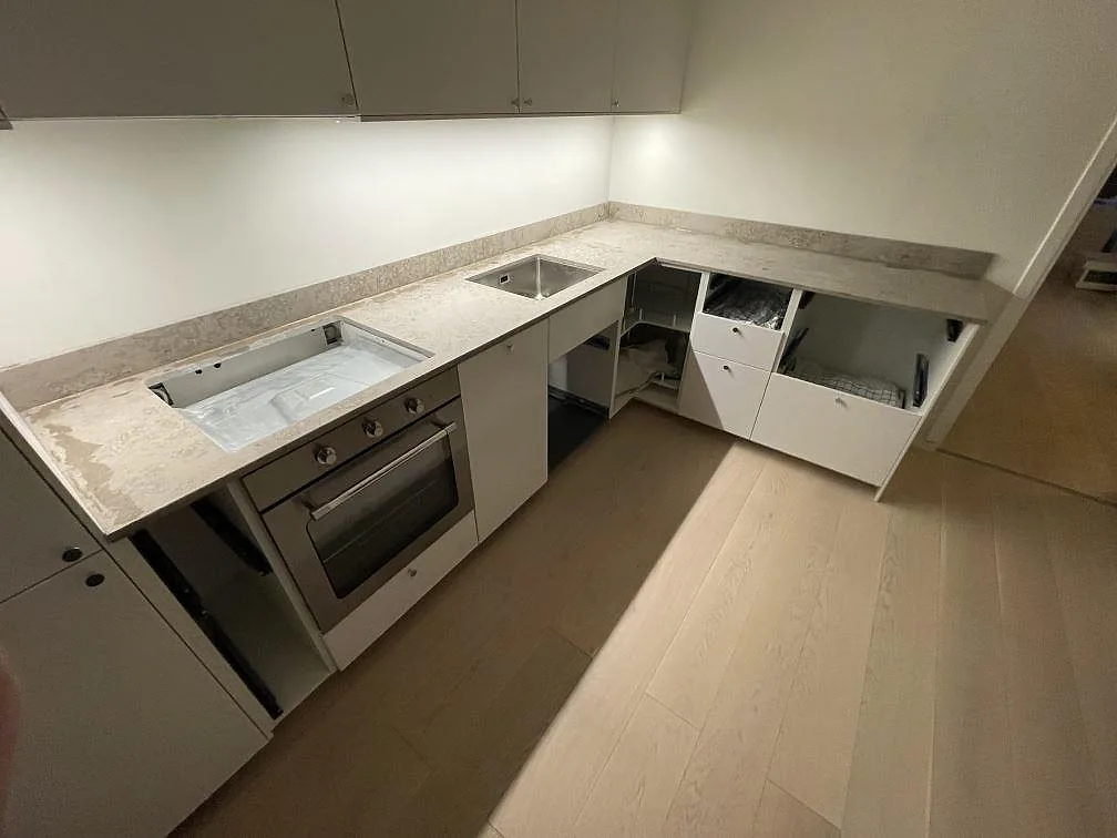 Jura Grey köksbänkskiva sedd över hela L-vinkeln, matt kalksten med levande ådring i ett kök i Sundbyberg.