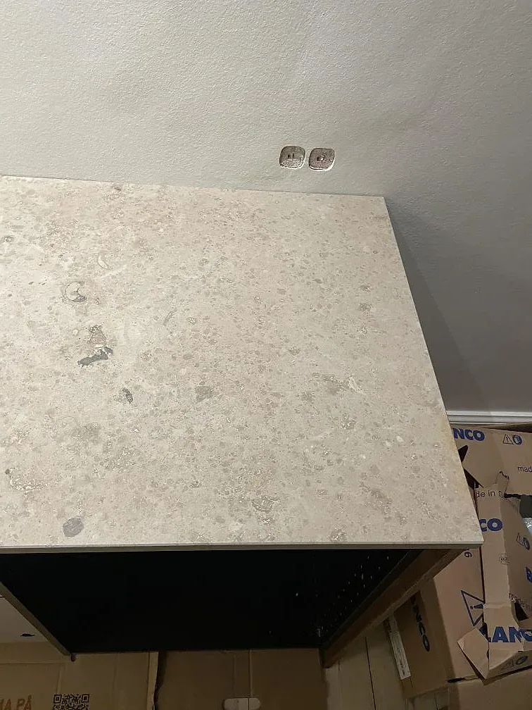 Ovanifrån på bänkskivan av Jura Grey kalksten med matt yta och eluttag i väggen i ett kök i Svendborg.
