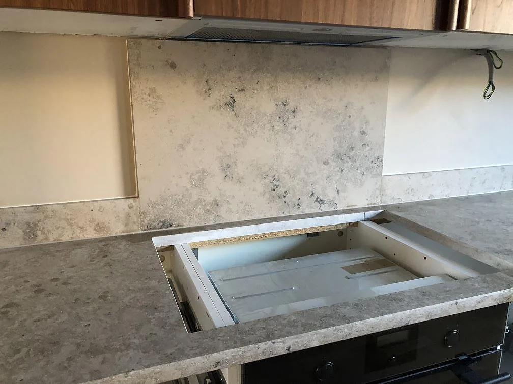 Matt köksbänkskiva i Jura Grey kalksten med uttag för häll och uppvikt stänkskydd under köksfläkten i ett kök i Torekov.