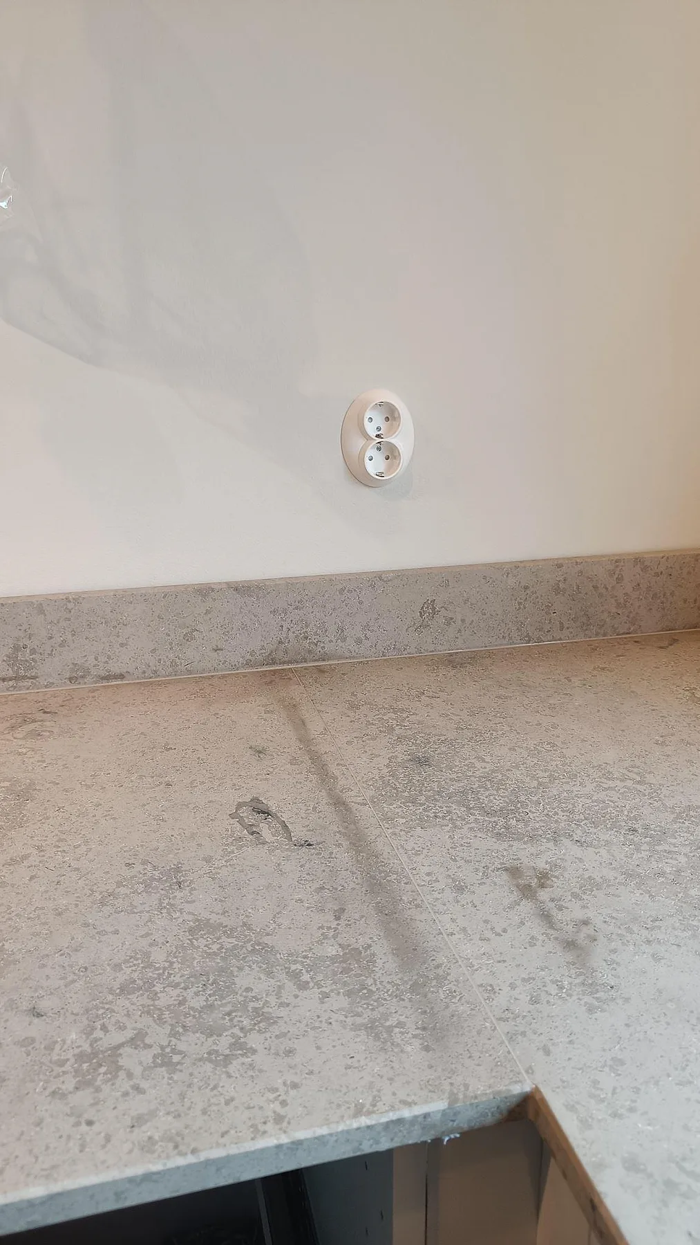 Detaljbild av matt Jura Grey köksbänkskiva och uppvikt stänkkant under montering i Västra Frölunda.