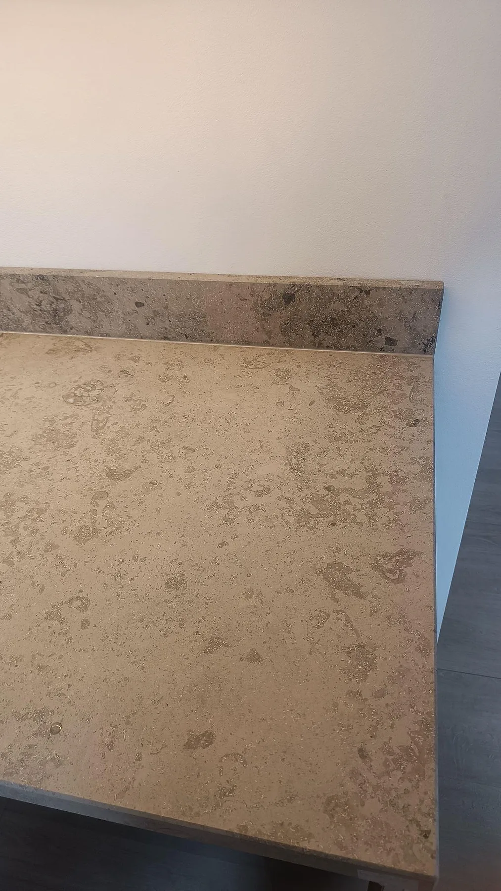 Detalj av matt Jura Grey kalksten på köksbänk med uppvikt stänkkant och synlig fossilstruktur i Varberg.