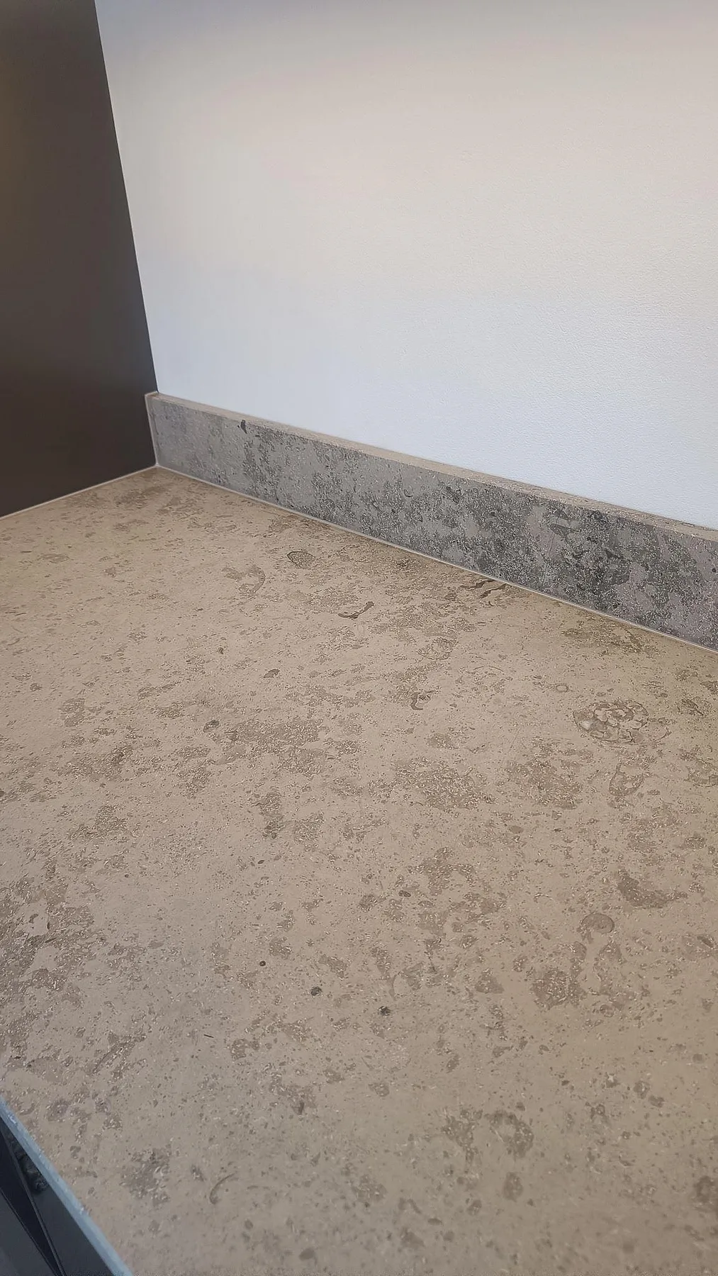 Närbild på köksbänkskiva i matt Jura Grey kalksten med fossilstruktur och stänkkant i Varberg.