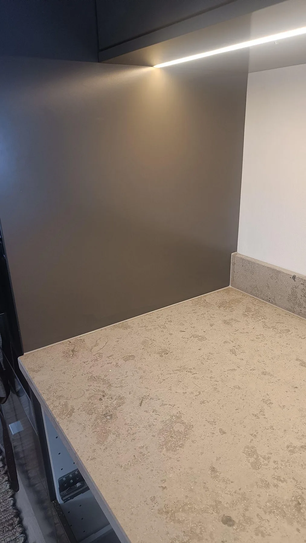 Köksbänk i matt Jura Grey kalksten med mörka skåp, väggpanel och uppvikt stänkkant i Varberg.