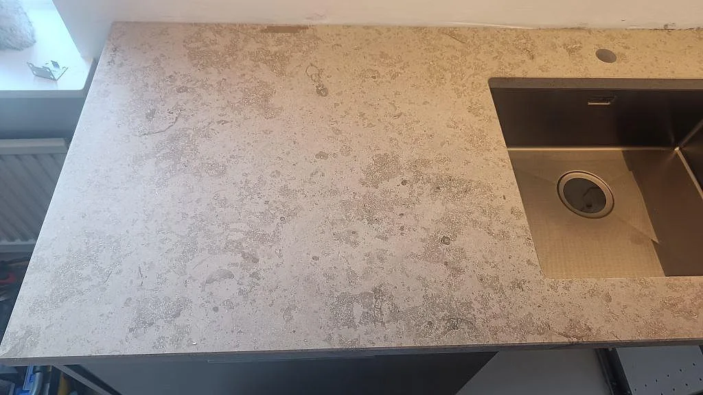 Topvy över matt Jura Grey kalksten med fossilstruktur och underlimmad rostfri diskho i Varberg.