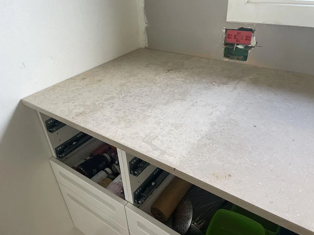 Detalj av matt Jura Grey kalksten som köksbänkskiva i Vedbæk, monterad mot vägg och fönster i ett kök under arbete.