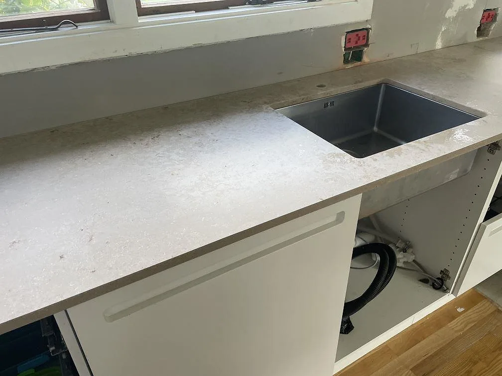 Närbild på köksbänkskiva i matt Jura Grey kalksten i Vedbæk med underlimmad rostfri diskho i rostfritt stål.