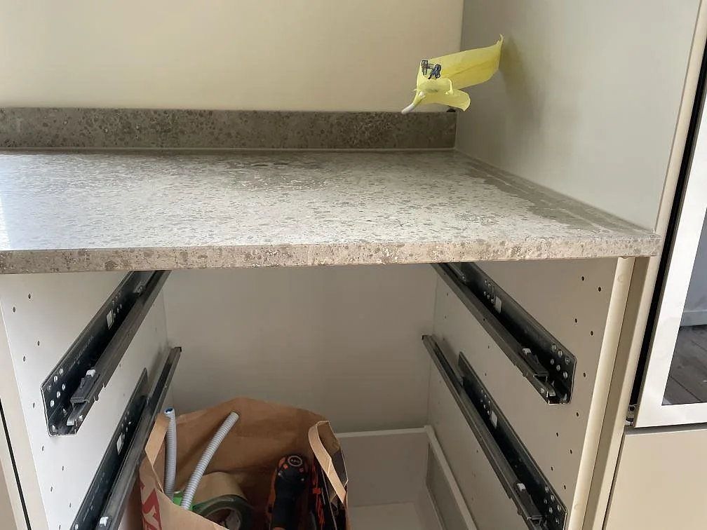 Detalj av matt Jura Grey kalksten med stänkkant, rak kantprofil och öppna köksstommar under montering i Ystad.