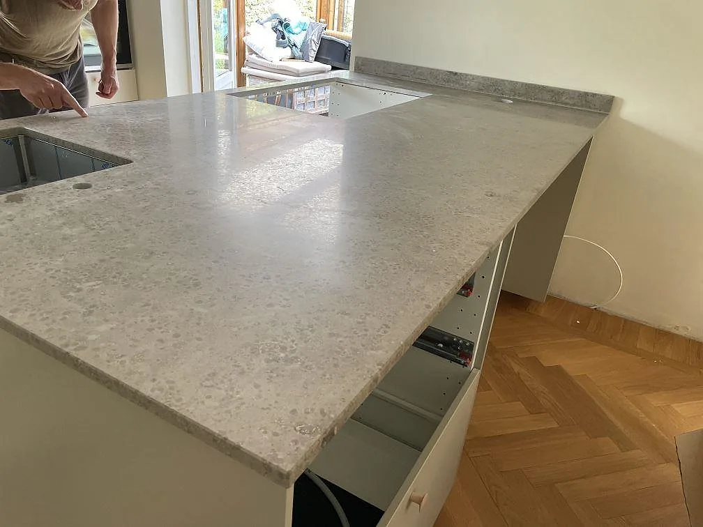 Köksbänkskiva i matt Jura Grey kalksten på halvö med hällurtag och uppvikt stänkkant i ett kök i Ystad.