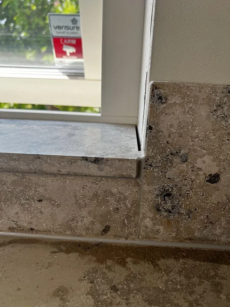 Närbild på matt Jura Grey kalksten och stänkkant vid fönster i köket i Ytterby.