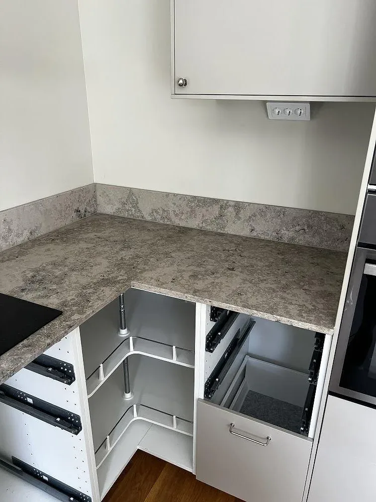 U-format kök i Ytterby med matt Jura Grey bänkskiva, uppvikt stänkkant och öppna köksstommar under montering.