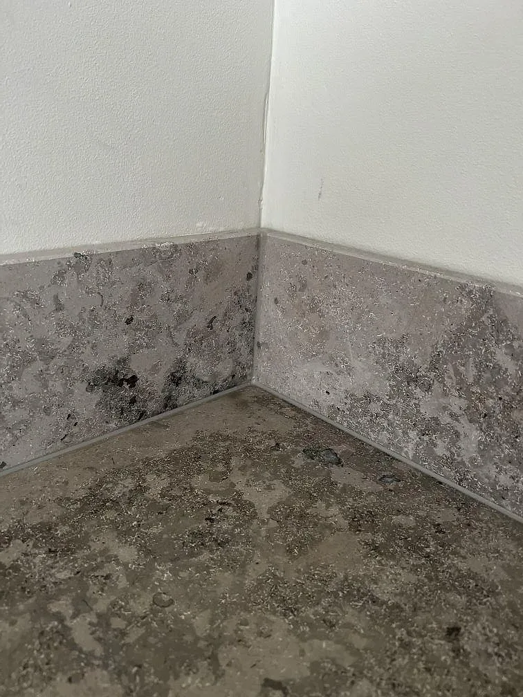 Närbild på hörn och uppvikt stänkkant i matt Jura Grey kalksten i ett kök i Ytterby.